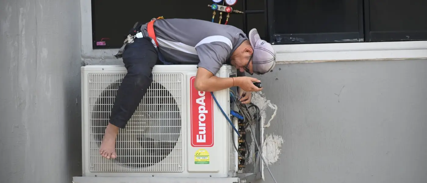 HVAC technician repairing an outdoor air conditioning unit