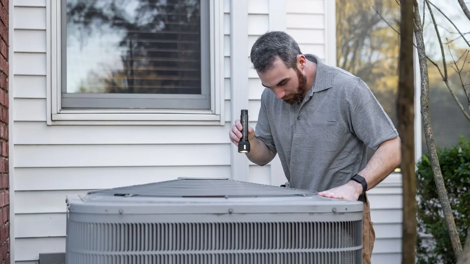 Northline Climate technician inspecting an outdoor air conditioning condenser unit at a home