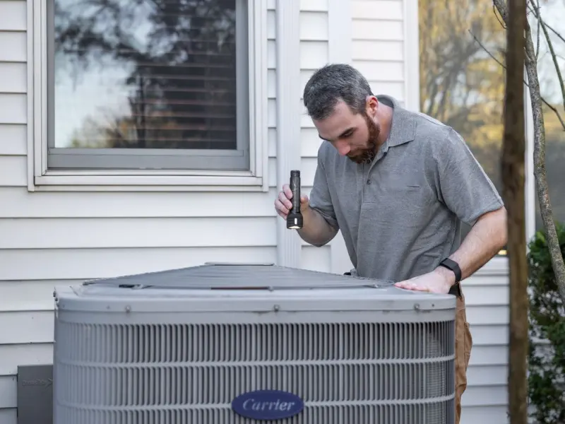 HVAC technician performing seasonal maintenance on a residential condenser unit