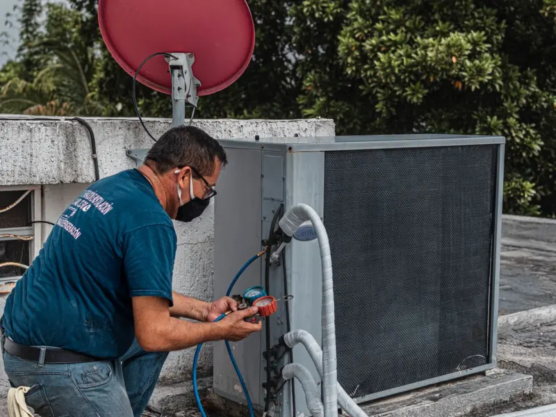 HVAC technician diagnosing a rooftop air conditioning unit with electrical meters