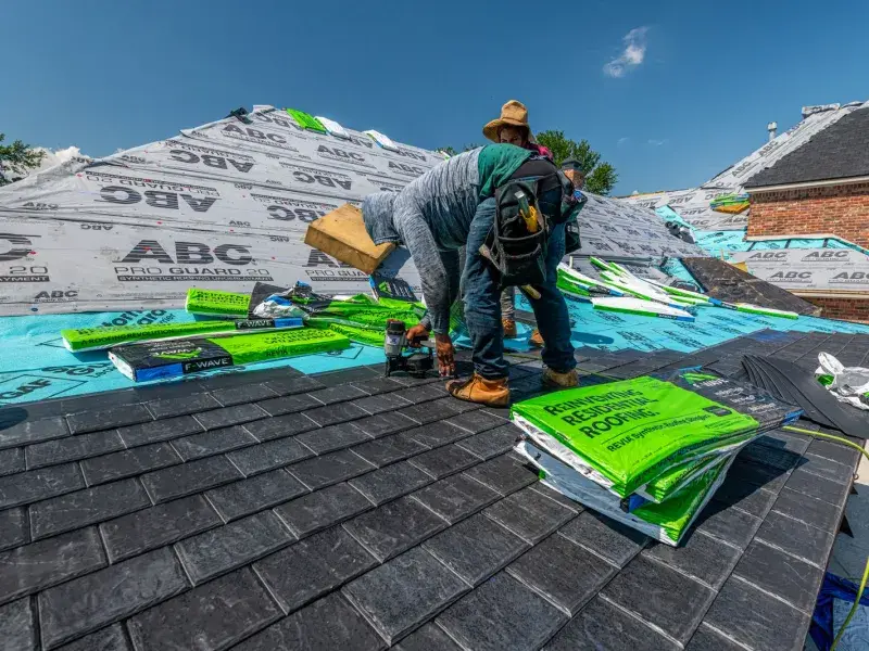 Roofing crew installing architectural asphalt shingles on a residential roof