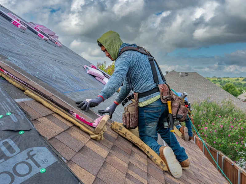 Roofer repairing storm damaged shingles and replacing missing tabs