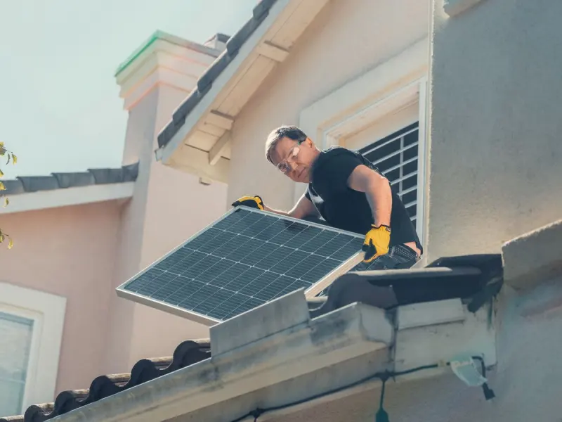 Solar technician mounting a photovoltaic panel array on a home roof