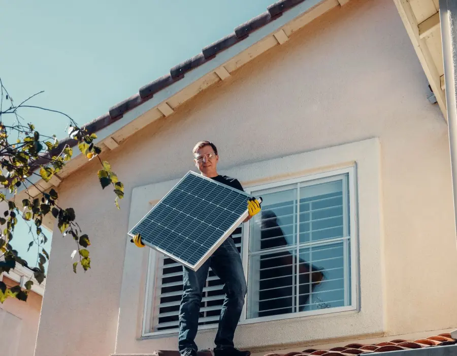 Solar installer carrying a photovoltaic panel during a residential installation